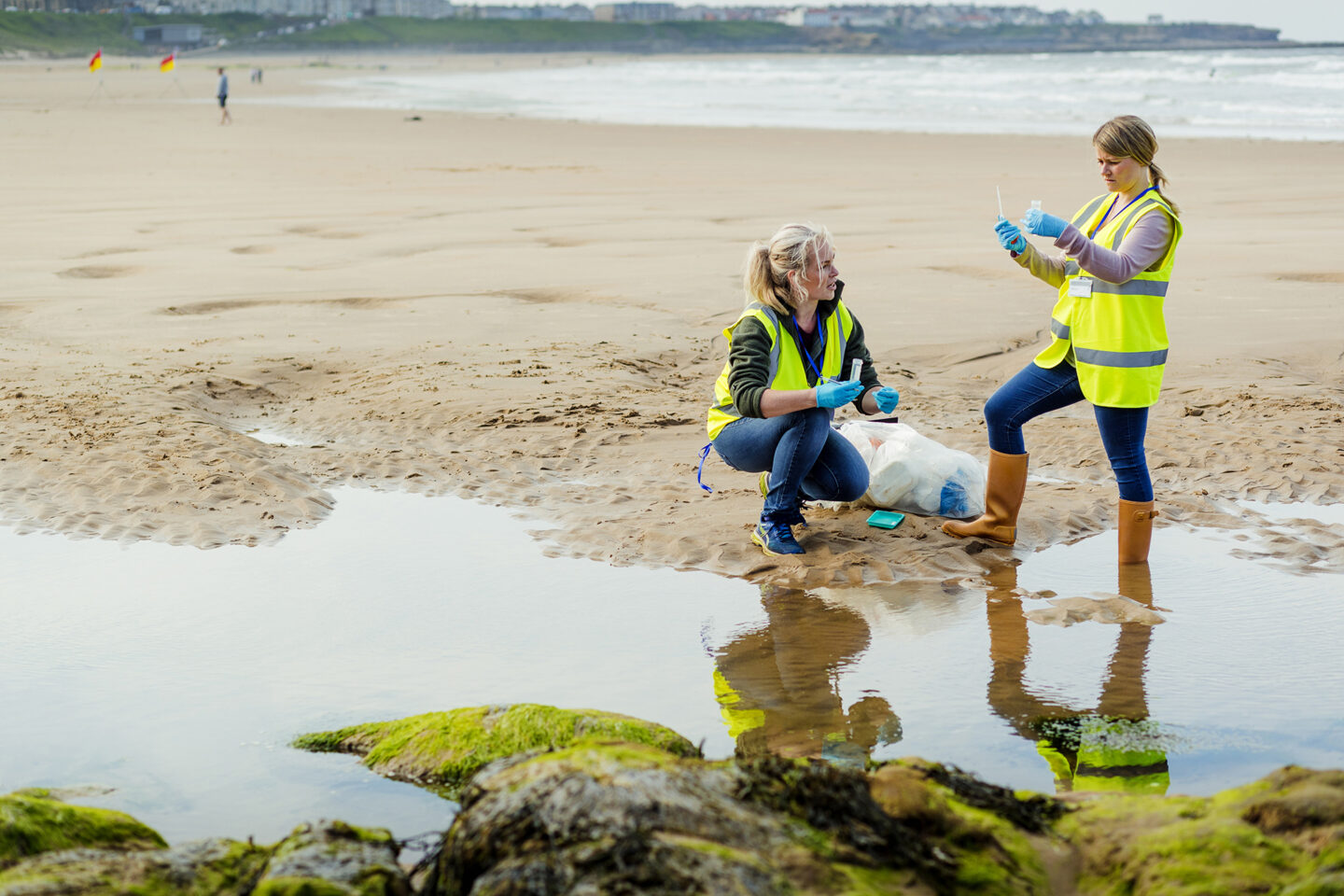 Two woman working near water taking samples