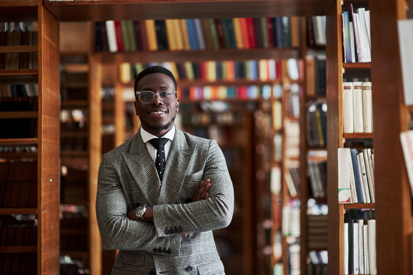 An African American man in a business suit standing in a library in the reading room man in a business suit standing in a library in the reading room.