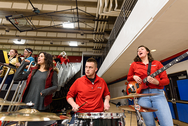 Pep band drummer and bass player shouting at team