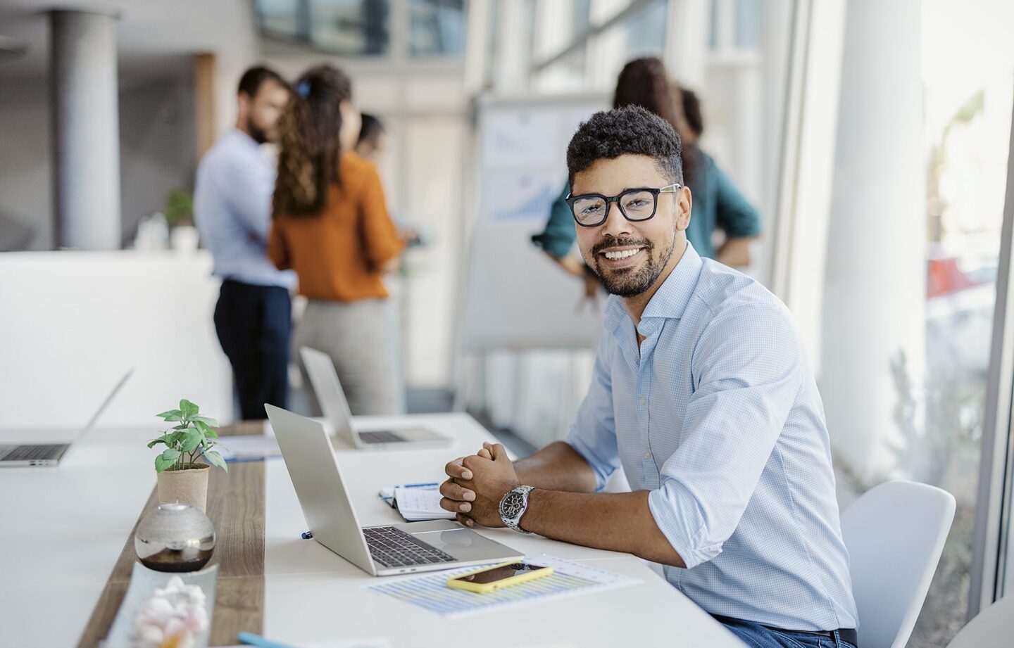 Man working in office with colleagues in the background