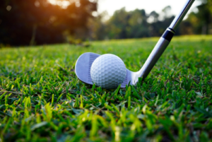 Golf ball on grass with golf club lined up to hit it