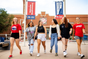 Six people walk toward the camera in with the Tivoli Student Union and MSU Denver banners in the background.