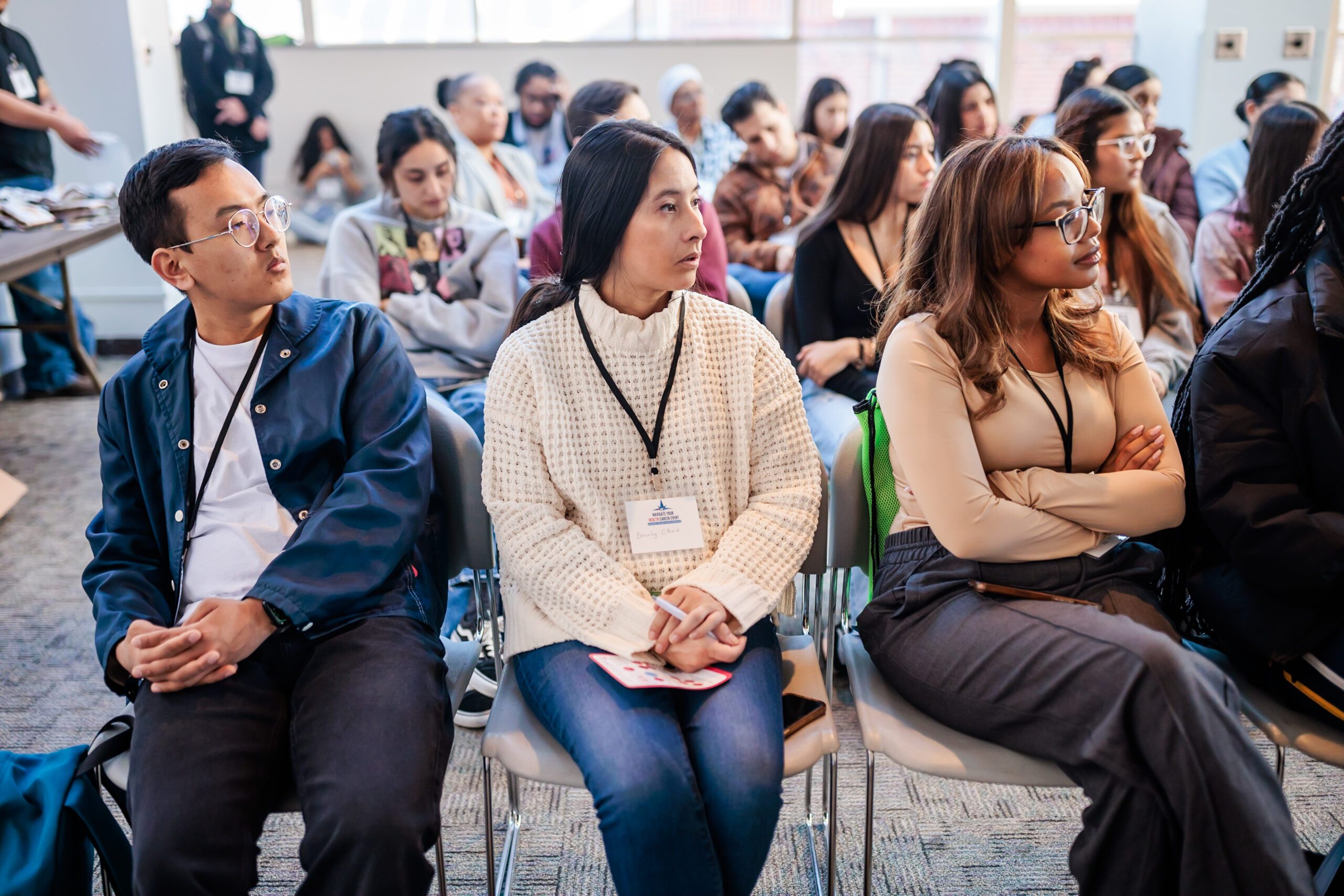 three students sitting in chairs looking right