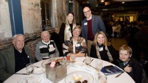 Jenny Price sitting with family and friends around a table at the MSU Denver Scholarship Dinner in the Tivoli Turnhalle