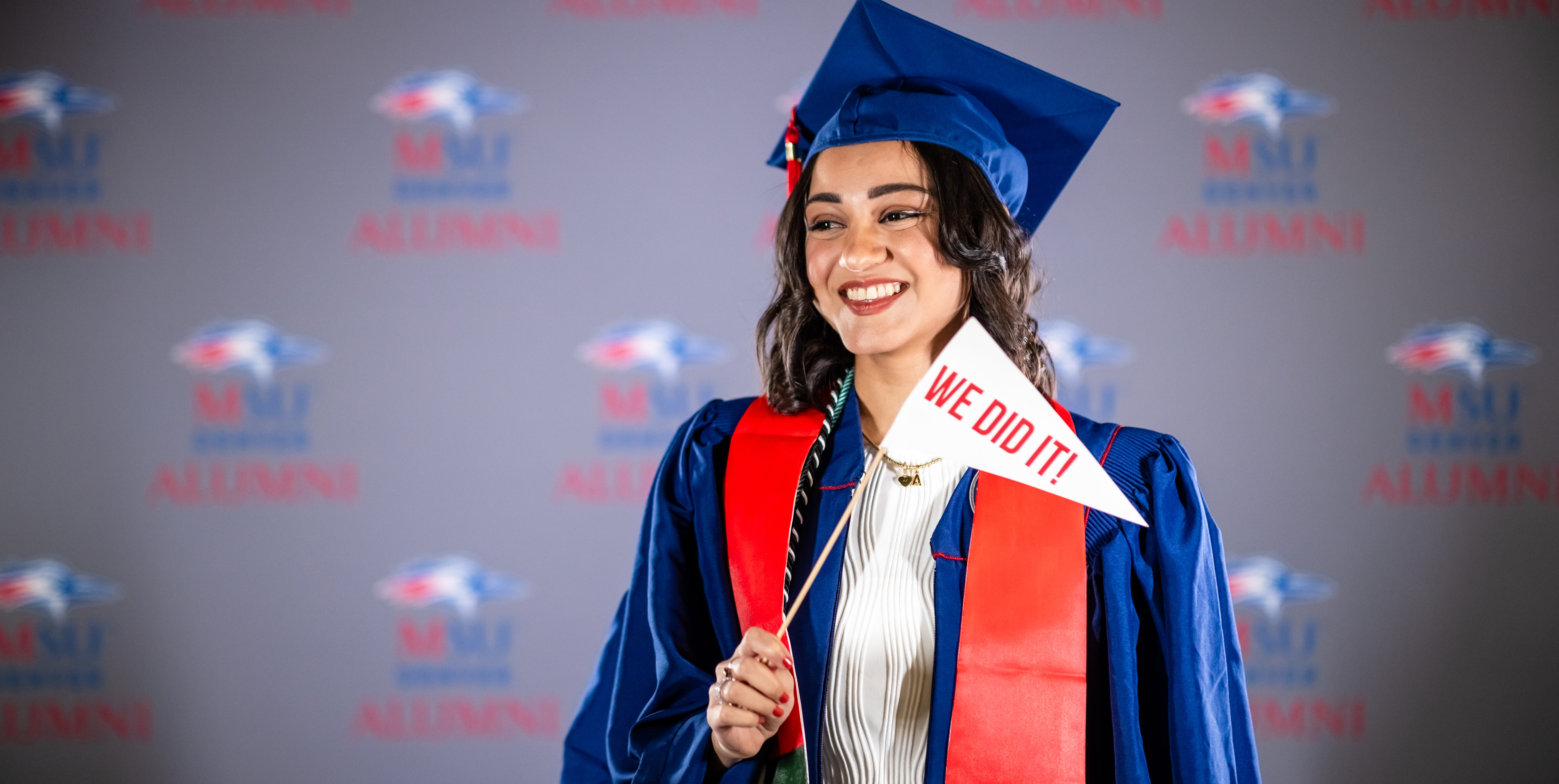 A grad holds up a 'We Did It' pennant in an MSU Denver photobooth