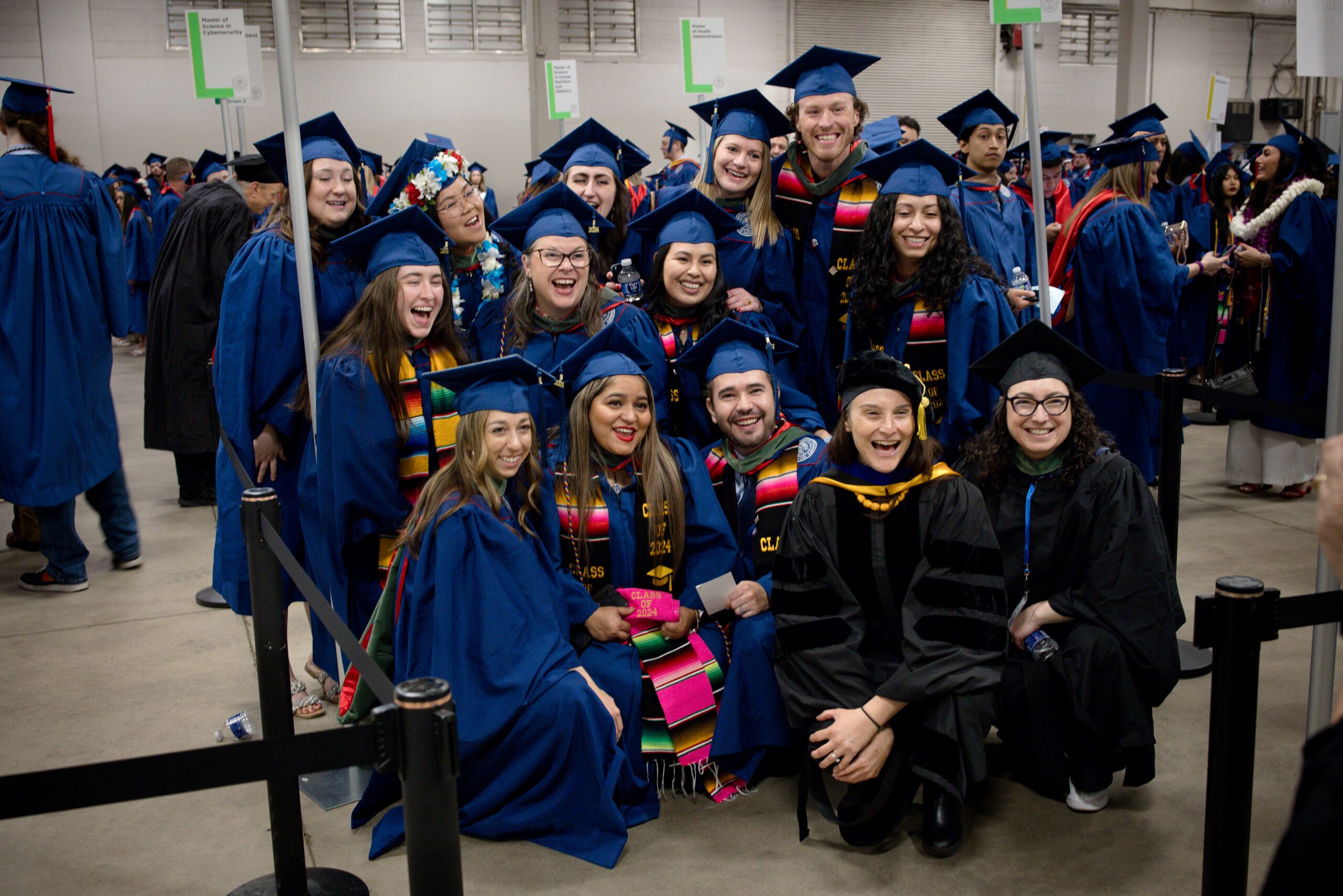 A group of graduates and Commencement marshals gather for a group photo.