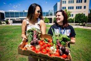 Alumna, Angelina Nguyen, left and Special Education major, Azure Dittenber showcase some of the vegetables offered at the Rowdy’s Corner Farm Stand on Thursday, July 11, 2024, on the JSSB lawn.