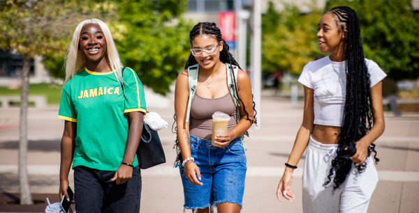 Three students walk together, smiling and laughing, outside on the MSU Denver campus