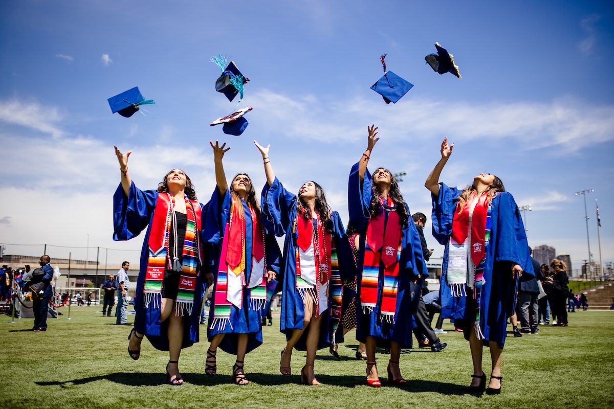 Five students toss their graduation caps in the air