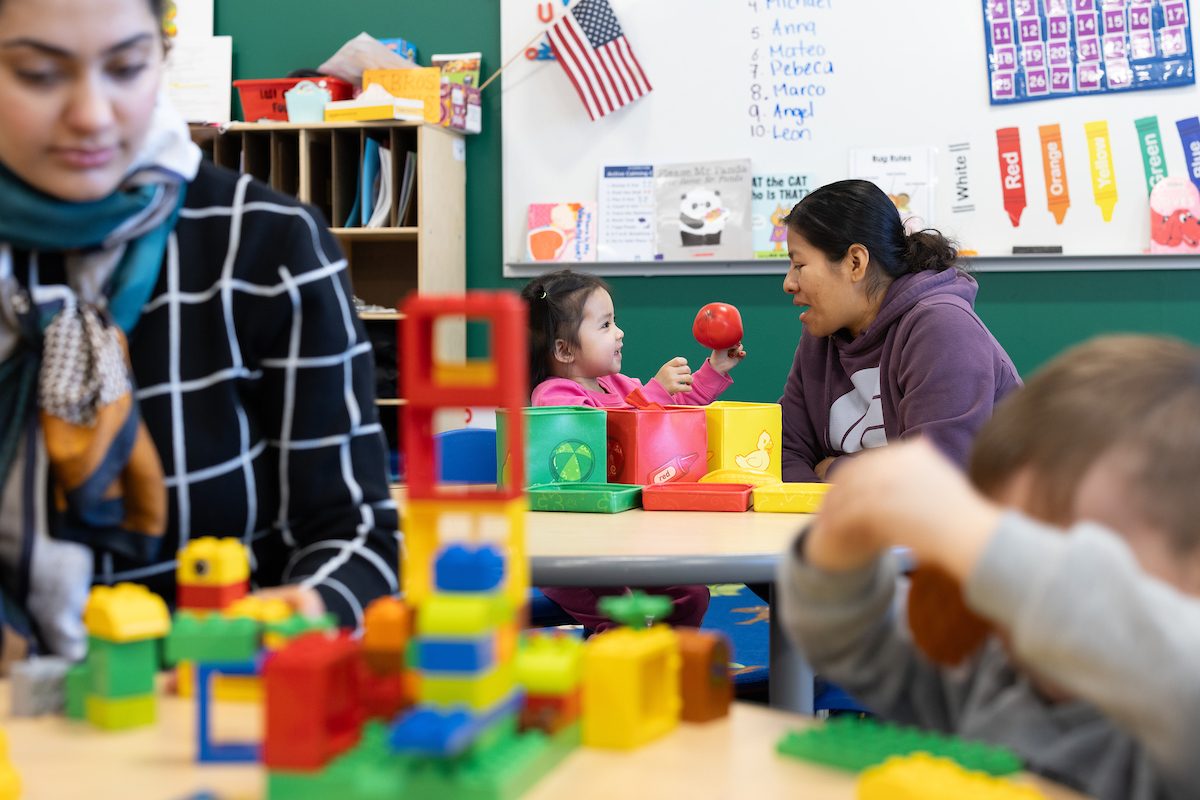 MSU Denver Early Family Literacy Program; Lisette Cabrera, MSU Denver student sits with a young child in a classroom holding a red ball