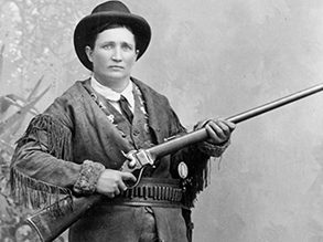 black and white old photo of Calamity Jane in a hat holding a rifle