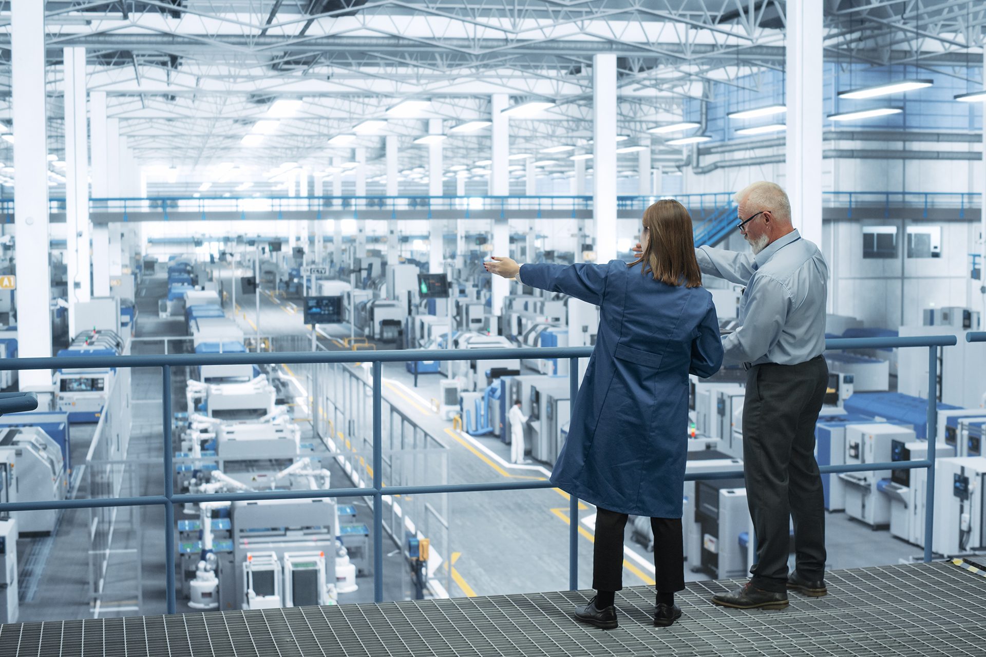 Facilities Manager talking with employee overlooking the inside of a facility.