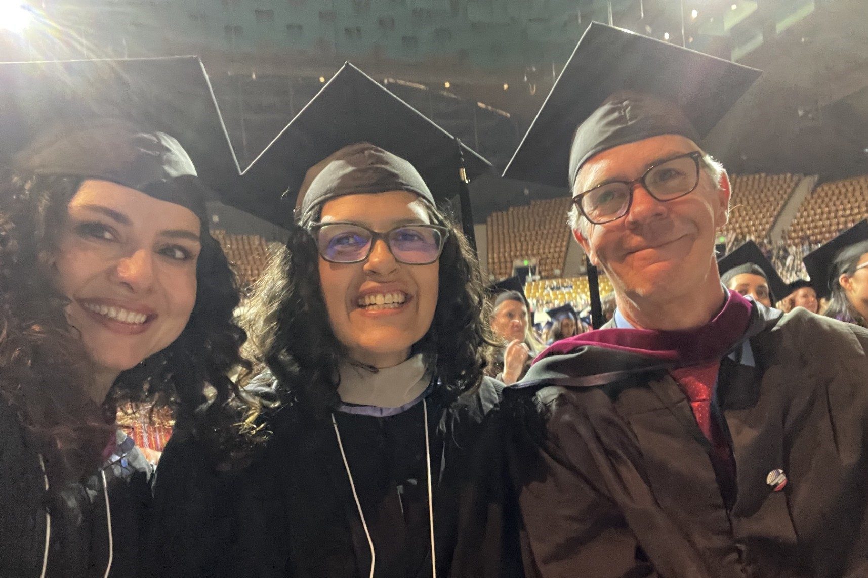 Journalism and Media Production Faculty in cap and gown (Left: Deanna Hirsch, Middle: Suree Towfighnia, Right: Joe Hammond) smile at MSU Denver Commencement