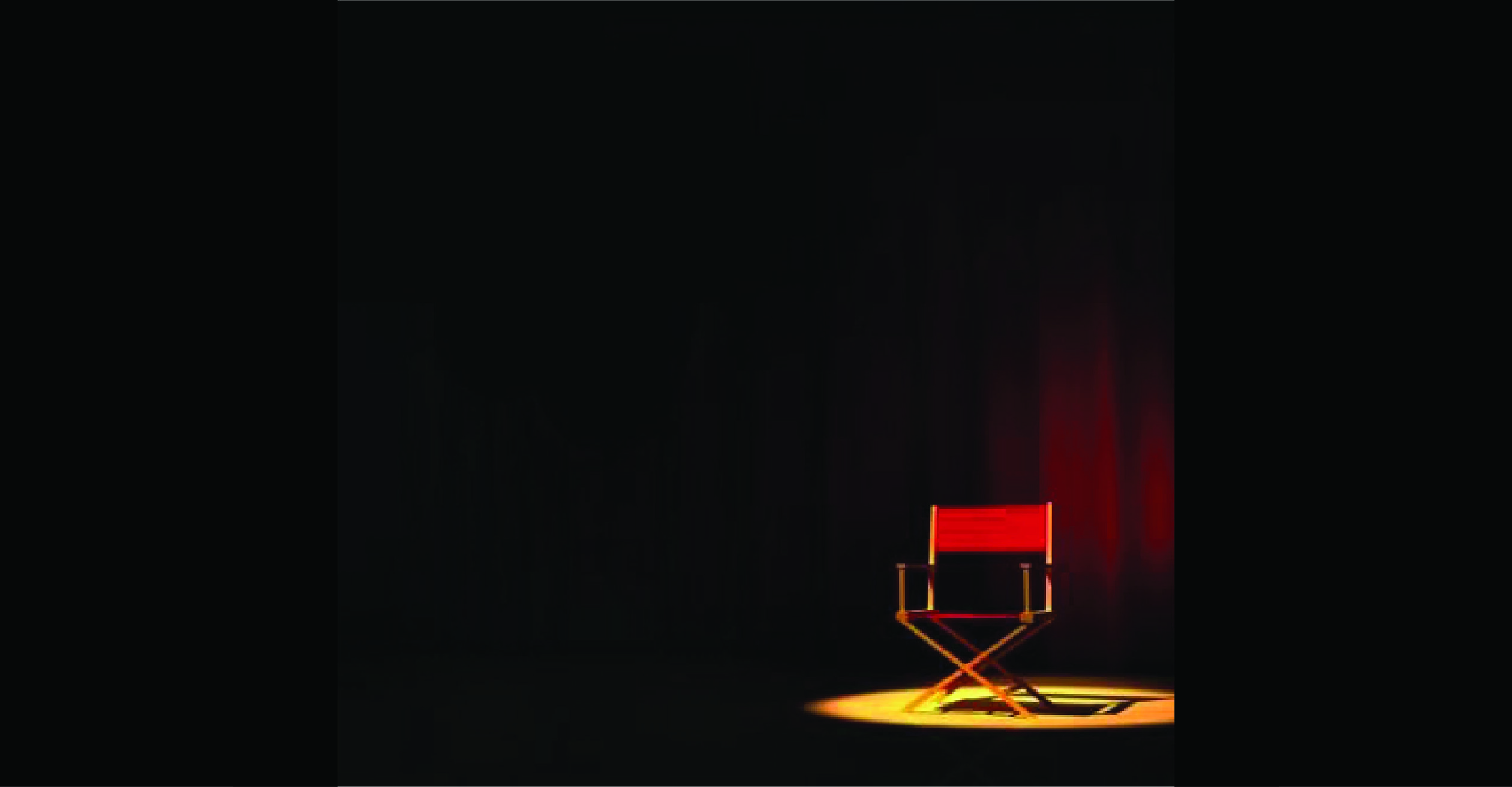 A red directing chair on a stage in a single spot light with a red curtain behind it.