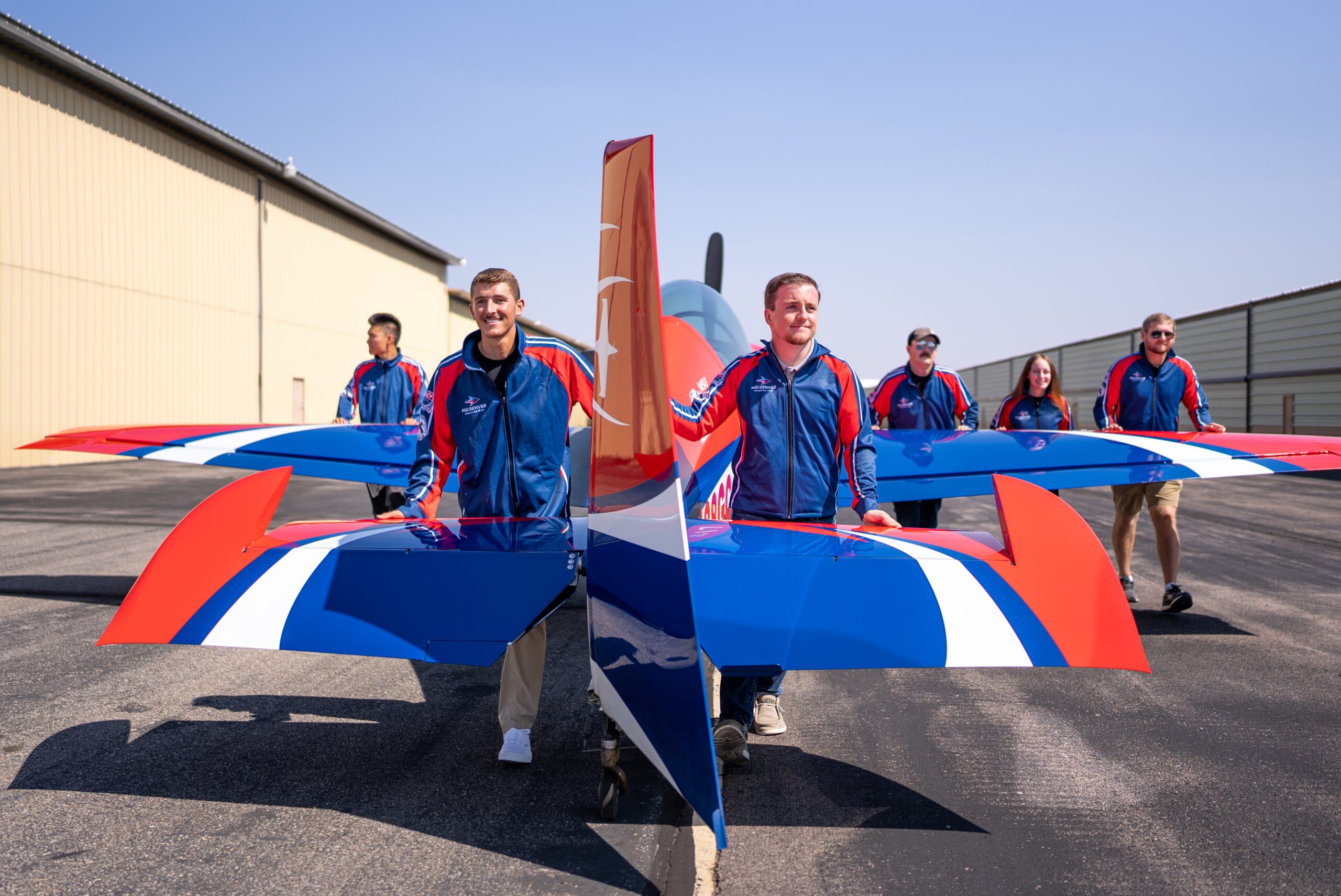 MSU Denver Aerobatics student, Brayden Berringer and Braeden Giltinan, and others pull the GB1 Gamebird to the runway.