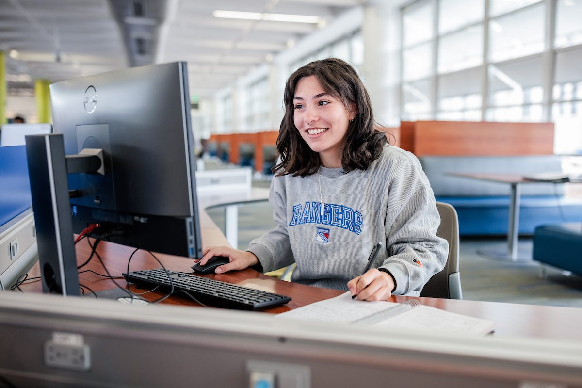 MSU Denver student, Abrianna Mangiamele, uses a computer while writing in a notebook