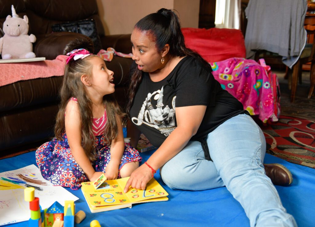 A parent and a child during a home visit making silly faces at each other