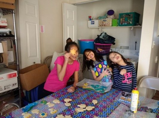 Three children holding cookies and smiling