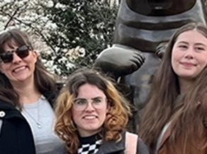 3 students standing in front of a bronze sculpture.