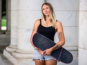 Mary Sullivan stands holding a skateboard.