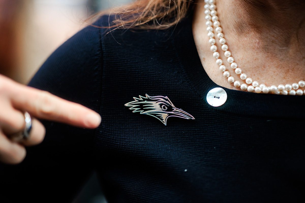 MSU Denver President, Janine Davidson, Ph.D., points to the Roadrunner brooch she's proudly wearing.