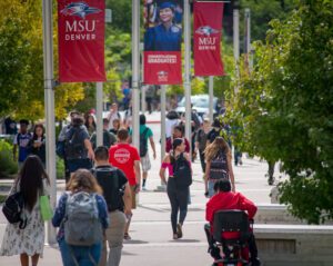 Students walking on campus near flagpoles with MSU Denver banners