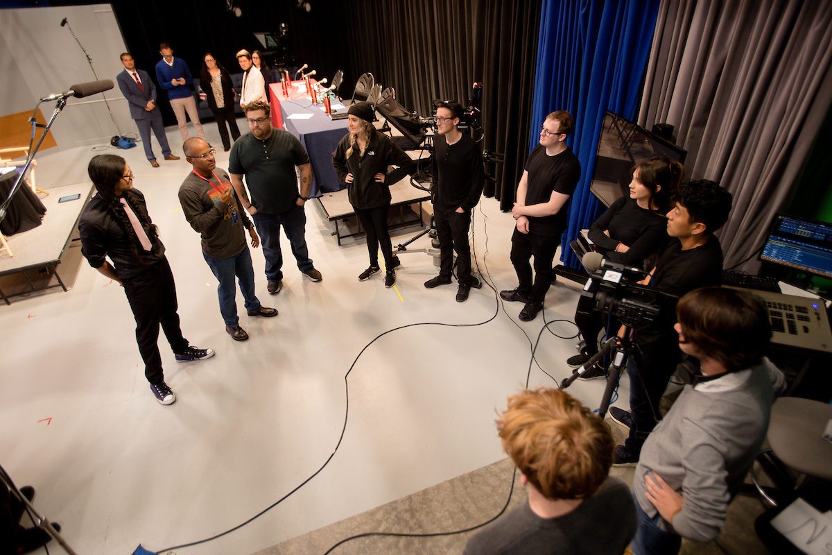 Assistant Professor, Alfredo Sanchez, congratulates and talks with journalism students after a successful taping.