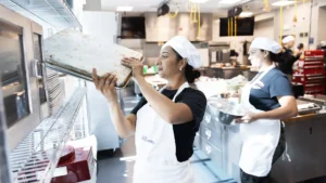 Greis Iriarte (left) and America Salon, students in the inaugural cohort of the WorkReady labor-integration program, put away pans in the School of Hospitality kitchen.