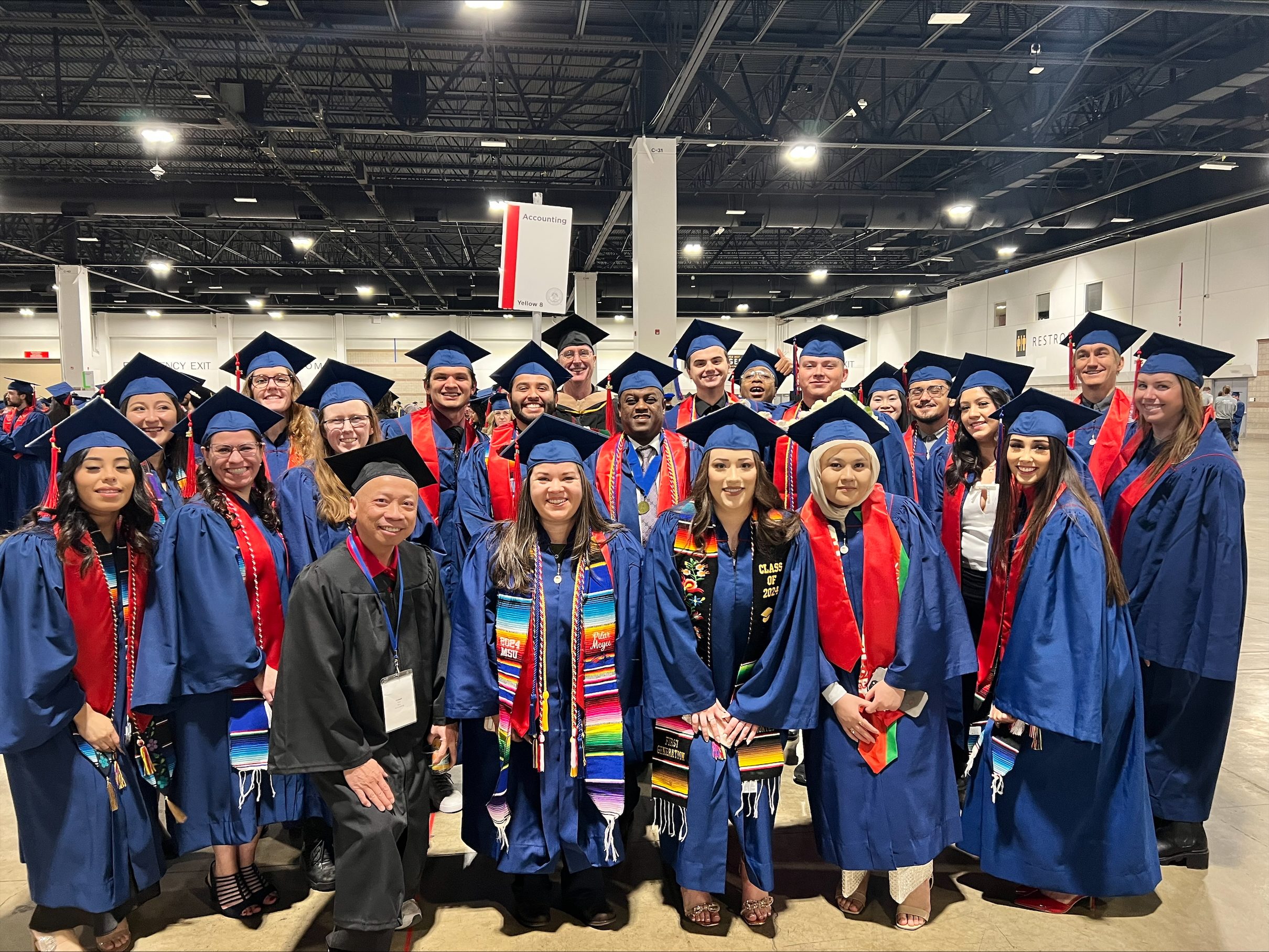 accounting group grads in regalia smiling at fall '24 commencement in assembly area