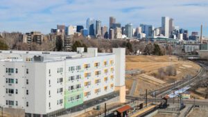 A drone shot of the denver city skyline on a sunny day with Arroyo village in the foreground