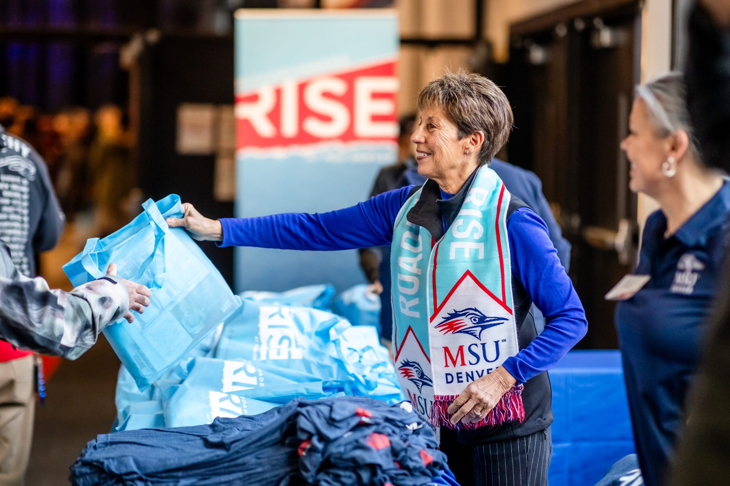 Passing out MSU Denver scarves at Roadrunners Rise Campaign Launch event